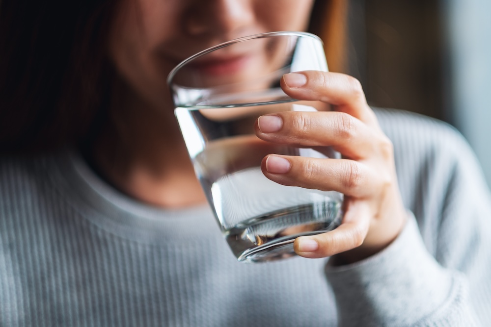 Closeup image of a woman holding a glass of water to drink