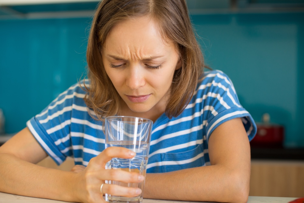 Person examining a glass of tap water before drinking.
